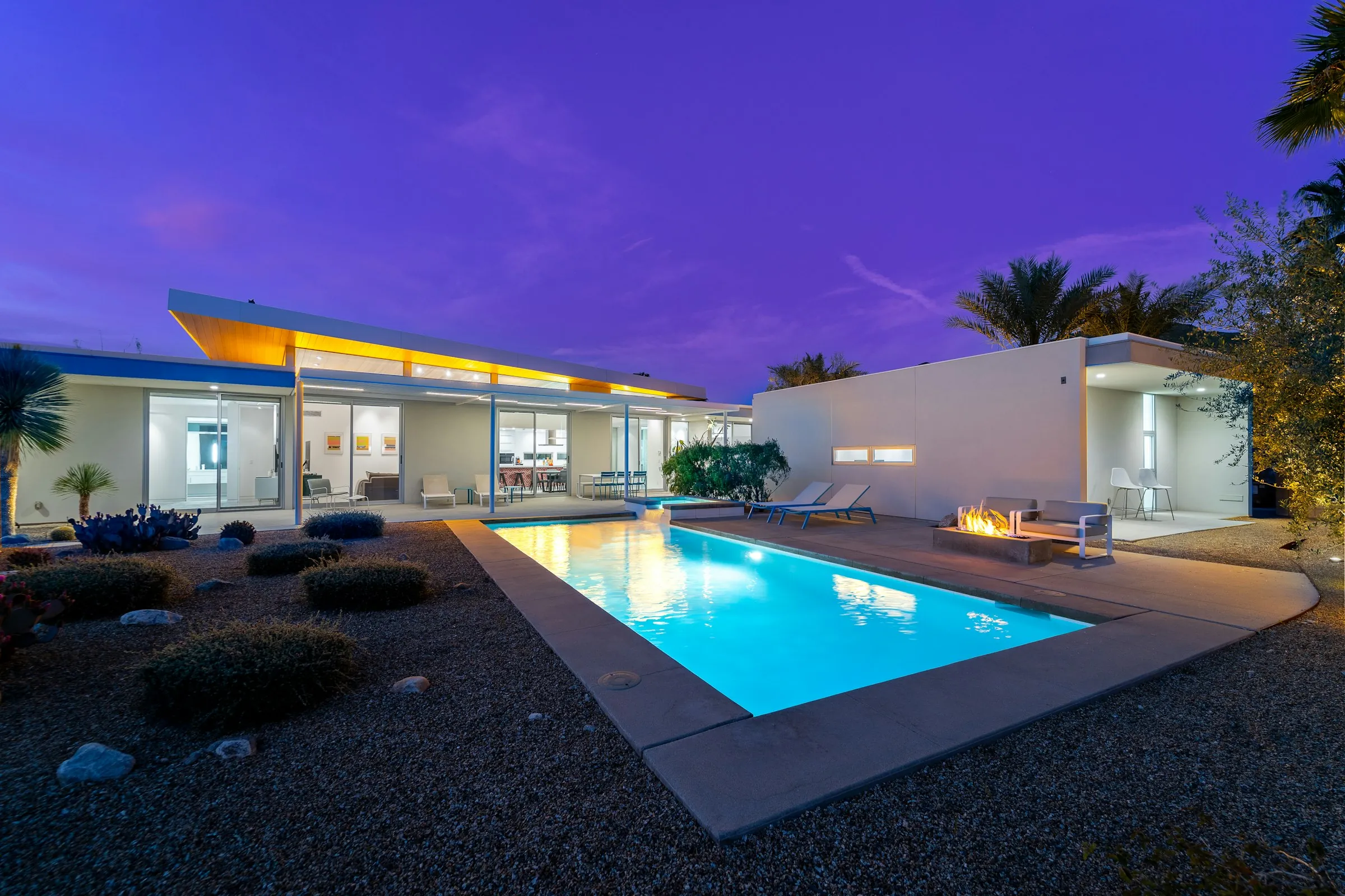 Modern Miami home with a lit pool at dusk